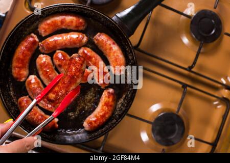 Cuisson de saucisses de viande sur une cuisinière de cuisine, vue rapprochée du dessus. Banque D'Images