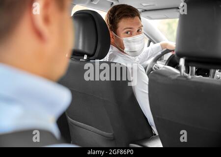 chauffeur de taxi dans le masque de protection du visage conduisant la voiture Banque D'Images