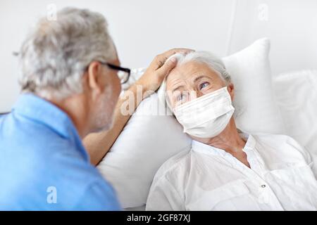 couple senior dans masques de visage réunion à l'hôpital Banque D'Images