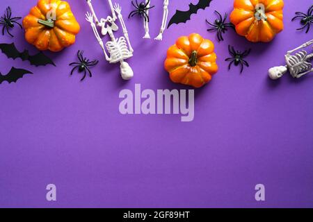 Bonne composition de fête d'Halloween avec citrouilles, squelettes, araignées, chauves-souris sur fond violet. Vue de dessus, plan d'appartement. Banque D'Images