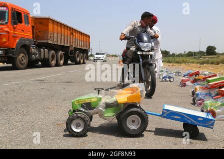 Beawar, Rajasthan, Inde, 24 août 2021: Vendeur de rue vendant des jouets de véhicule tandis que des véhicules lourds passent sur l'autoroute nationale Ahmedabad-Delhi à Beawar. Crédit : Sumit Saraswat/Alay Live News Banque D'Images