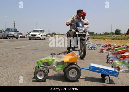 Beawar, Rajasthan, Inde, 24 août 2021: Vendeur de rue vendant des jouets de véhicule tandis que de nombreux véhicules passent sur l'autoroute nationale Ahmedabad-Delhi à Beawar. Crédit : Sumit Saraswat/Alay Live News Banque D'Images