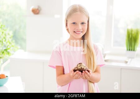 Photo de jeune fille heureuse petite sourire bonne humeur tenir les mains gâteau cuire à l'intérieur maison cuisine maison Banque D'Images