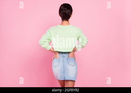 Arrière vue arrière photo de la jeune fille colonne vertébrale mains dans la poche incognito anonym isolé sur fond rose couleur Banque D'Images