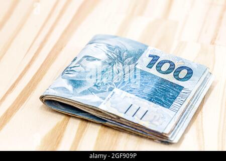 Billets de banque d'argent brésilien, 100 billets de reais, sur fond de bois clair et rustique. Concept d'économies ou d'économies. Banque D'Images