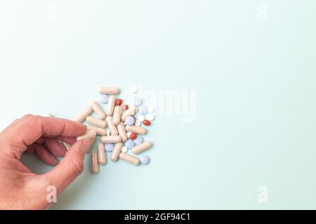 Main prenant des pilules d'une pile de pilules assorties sur un fond bleu, copier l'espace. Concept de santé mentale. Médicament pour la dépression. Trouble nerveux t Banque D'Images