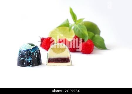 Bonbons au chocolat en cutaway. Framboise, lime et basilic sur fond blanc. Bonbons faits main. Banque D'Images