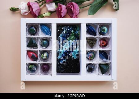Un ensemble de bonbons faits main dans un emballage blanc de fête. Design de l'espace. Bonbons sur fond clair et décor de fleurs roses Banque D'Images