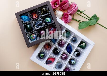 Un ensemble de bonbons faits main dans un emballage festif. Design de l'espace. Bonbons sur fond clair et décor de fleurs roses. Boîte noire et blanche Banque D'Images