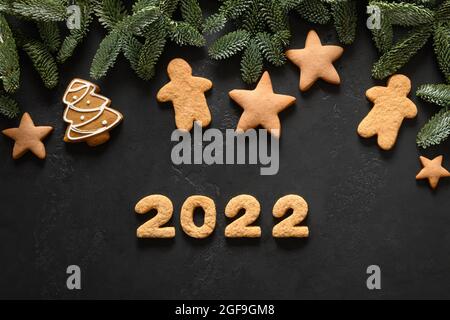 Les fêtes de Noël ont glacé des biscuits et date 2022 sur fond noir. Bonne Année. Vue de dessus. Pose à plat. Banque D'Images