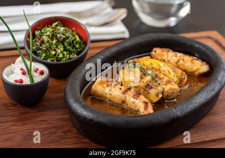 Pieuvre grillée avec salade de quinoa sur une assiette en pierre noire. Banque D'Images