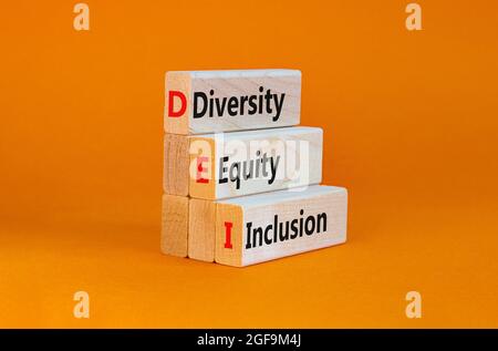 DEI, diversité, équité, symbole d'inclusion. Blocs en bois avec des mots DEI, diversité, équité, inclusion sur fond orange magnifique. Business, DEI, di Banque D'Images