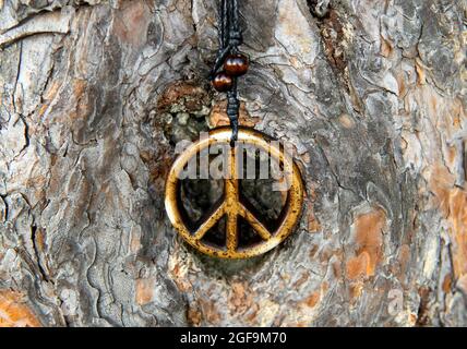 Gros plan d'un collier signe de paix sur un arrière-plan texturé d'écorce d'arbre, foyer sélectif Banque D'Images