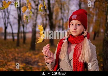 adolescente dans un chapeau rouge et un foulard dans un parc d'automne. Banque D'Images