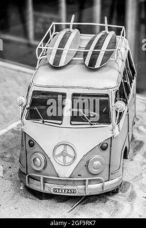 Oldtimer bus avec deux planches de surf sur la plage de sable. Peu de bus se déplace. Banque D'Images