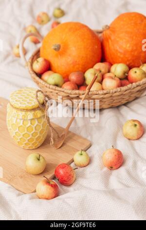 L'automne encore la vie dans des couleurs chaudes, l'esthétique de chalet. Un pot de miel, de citrouille et de pommes dans un panier en osier sur un tissu naturel. Produits agricoles Banque D'Images