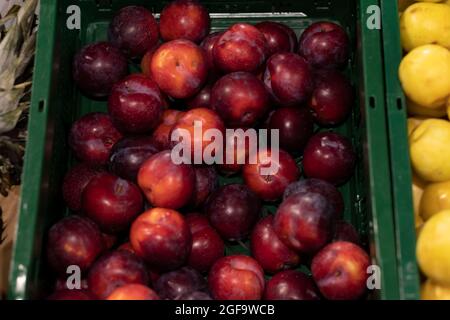 Prunes rouges comme arrière-plan, dans un marché. Banque D'Images