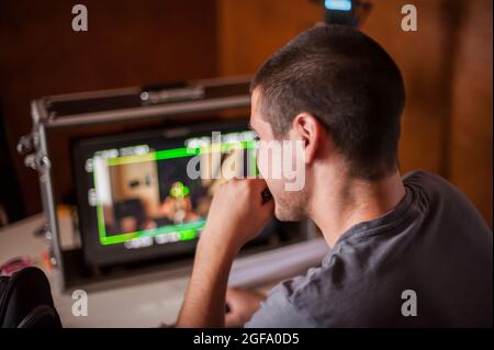 Dans les coulisses. Le réalisateur supervise et contrôle le tournage du film sur l'écran lcd depuis le studio de montage de film extérieur. Analogique a Banque D'Images