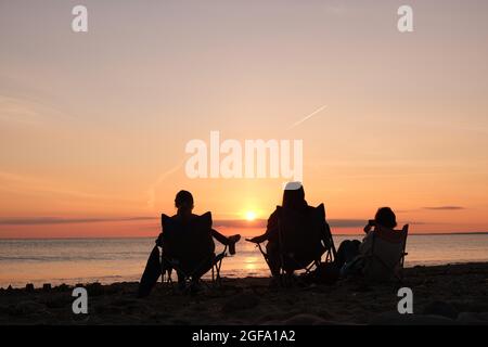 Gower, Swansea, Royaume-Uni. 24 août 2021. Météo au Royaume-Uni : en profitant de la vue, les gens se rassemblent pour regarder le soleil se coucher sur une soirée sèche, belle et ensoleillée à la plage de Llangennith sur la péninsule de Gower. Les perspectives pour les prochains jours sont pour le même beau temps avec quelques sorts chauds.Credit: Gareth Llewelyn/Alamy Live News Banque D'Images