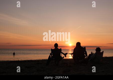 Gower, Swansea, Royaume-Uni. 24 août 2021. Météo au Royaume-Uni : en profitant de la vue, les gens se rassemblent pour regarder le soleil se coucher sur une soirée sèche, belle et ensoleillée à la plage de Llangennith sur la péninsule de Gower. Les perspectives pour les prochains jours sont pour le même beau temps avec quelques sorts chauds.Credit: Gareth Llewelyn/Alamy Live News Banque D'Images