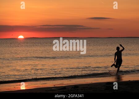 Gower, Swansea, Royaume-Uni. 24 août 2021. Météo au Royaume-Uni: Un garçon aime arnaqueter les hilades sous un soleil couchant, lors d'une soirée sèche, fine et ensoleillée à la plage de Llangennith sur la péninsule de Gower. Les perspectives pour les prochains jours sont pour le même beau temps avec quelques sorts chauds.Credit: Gareth Llewelyn/Alamy Live News Banque D'Images