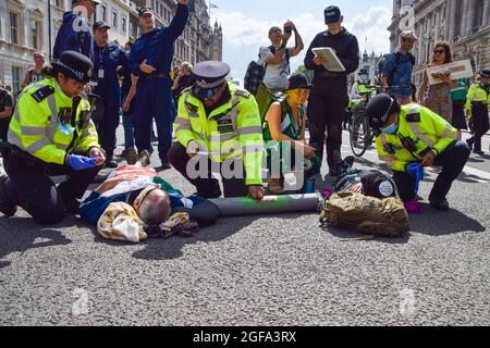 Londres, Royaume-Uni. 24 août 2021. La police se prépare à retirer et à arrêter les manifestants de la rébellion qui se sont enlisés sur la route devant HM Revenue & Customs. Les manifestants se sont rassemblés à Westminster pour la deuxième journée complète de leur campagne de deux semaines, la rébellion impossible, appelant le gouvernement britannique à agir de manière significative sur la crise climatique et écologique. (Crédit : Vuk Valcic / Alamy Live News) Banque D'Images