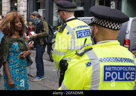 Londres, Royaume-Uni. 23 août 2021. Valerie Brown, candidate à la Mayorale Burning Pink London, s'adresse à un officier de la police métropolitaine lors d'un cordon autour des militants écologistes de la rébellion d'extinction dans la région de Covent Garden, le premier jour de manifestations impossibles de la rébellion. Extinction la rébellion appelle le gouvernement britannique à mettre fin à tous les nouveaux investissements dans les combustibles fossiles avec effet immédiat. Crédit : Mark Kerrison/Alamy Live News Banque D'Images