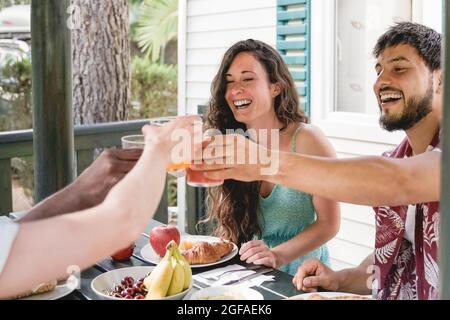 Les gens multiraciaux faisant la bonne partie de pique-nique de petit-déjeuner ayant plaisir manger et boire du jus à la ferme de campagne - joie et amis style de vie ou Banque D'Images