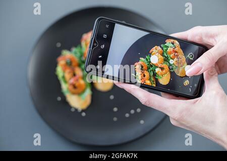 Image pour un style de vie. Une fille prend des photos d'une bruschetta à partir d'un buffet sur son téléphone Banque D'Images