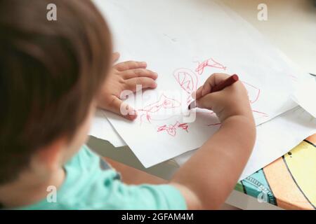 Un tout-petit garçon qui dessine dans une table. Vue de dessus. Banque D'Images