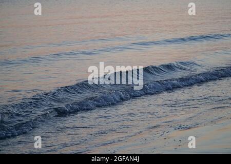 East Wittering, Royaume-Uni, 23 août 2021 : les vagues douces sur la plage de sable au crépuscule reflètent les bleus et les roses dans le ciel juste après le coucher du soleil. La mer est l'Engli Banque D'Images