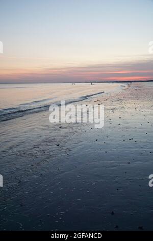 East Wittering, Royaume-Uni, 23 août 2021 : les vagues douces sur la plage de sable au crépuscule reflètent les bleus et les roses dans le ciel juste après le coucher du soleil. La mer est l'Engli Banque D'Images