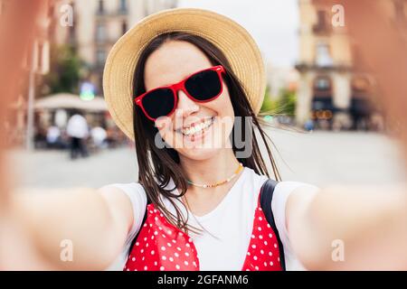 Bonne jeune femme en train de fabriquer un selfie avec un smartphone dans la rue de la ville Banque D'Images