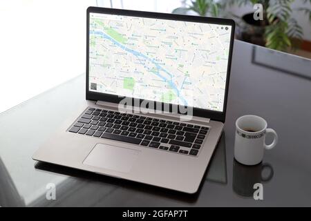 Ordinateur portable au-dessus de la table avec plan de la ville de Paris à l'écran. Utilisation de la page Web Google Maps. Une tasse à café sur un côté de l'ordinateur. Banque D'Images