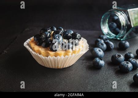 Tarte aux myrtilles sur fond sombre. Gâteau aux myrtilles sur une table de service noire avec baies éparses Banque D'Images