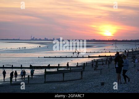 East Wittering, Royaume-Uni, 23 août 2021 : les gens et les chiens apprécient le temps sec sur la plage d'East Wittering dans West Sussex pendant que le soleil se couche sur le Solen Banque D'Images