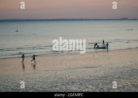 East Wittering, Royaume-Uni, 23 août 2021 : les gens et les chiens apprécient le temps sec sur la plage d'East Wittering dans West Sussex pendant que le soleil se couche sur le Solen Banque D'Images