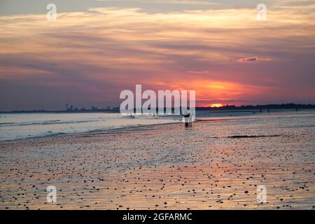 East Wittering, Royaume-Uni, 23 août 2021 : les gens et les chiens apprécient le temps sec sur la plage d'East Wittering dans West Sussex pendant que le soleil se couche sur le Solen Banque D'Images