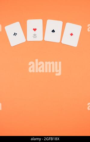 Vue de dessus de quatre cartes alignées ace isolées sur un fond orange avec espace libre Banque D'Images
