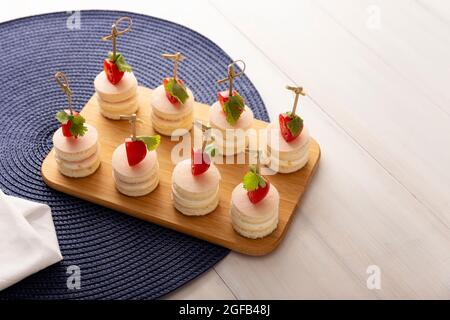 Délicieux en-cas de fête. Mini sandwiches ronds au jambon et au fromage décorés de tomates cerises sur un bâton de bambou Banque D'Images