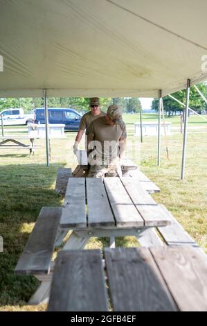 Des soldats de l'armée américaine affectés à la Force opérationnelle McCoy déplacent des bancs sous des tentes en vue de l'arrivée des Afghans à la base de la Garde nationale aérienne de Volk Field, Wisconsin, le 21 août 2021. Le ministère de la Défense, à l'appui du ministère d'État, fournit des services de transport et des logements temporaires à l'appui de l'opération alliés refuge. Cette initiative s'inscrit dans le cadre de l'engagement de l'Amérique envers les citoyens afghans qui ont aidé les États-Unis et leur fournit un soutien essentiel dans des lieux sûrs à l'extérieur de l'Afghanistan. (É.-U. Photo de l'armée par le sergent d'état-major. Ryan Rayno, 181e train multifonctionnel Banque D'Images