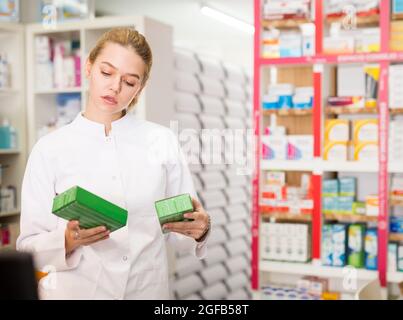 Portrait d'une femme souriante et sympathique, en manteau blanc, travaillant en pharmacie Banque D'Images