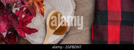 Sirop d'érable ingrédient sucré pour les recettes de desssert, liquide s'écoulant de la cuillère en bois sur bois de bois rustiques cabane à sucre bannière panoramique avec buffle Banque D'Images