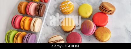 De nombreux macarons à la boulangerie dans une boîte cadeau. Bannière panoramique de desserts sucrés français vue de dessus Banque D'Images