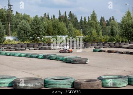 Une fille ou une femme dans un casque roule un kart sur une piste spéciale. Banque D'Images