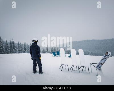 Vue arrière d'un skieur au sommet d'une montagne qui regarde la forêt de sapins enneigée à l'horizon. Journée d'hiver enneigée à la station de ski de Bukovel, en ukrainien Banque D'Images