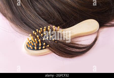 Cheveux longs et droits bruns brillants avec brosse en bois. Soins capillaires, soins, coiffage et concept spa Banque D'Images