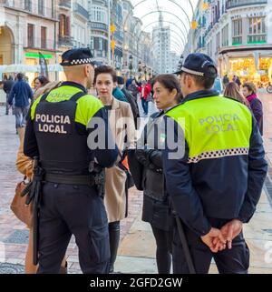 Deux policiers municipaux parlent aux visiteurs de la Plaza de la Constitucion, Malaga, Costa del sol, province de Malaga, Andalousie, Sud de l'Espagne. Banque D'Images