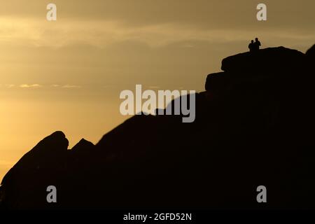 Des formations rocheuses spectaculaires de bordure de panneau dans le quartier de pic sont silhouettés contre le ciel doré d'un beau coucher de soleil. Un couple se trouve en haut Banque D'Images