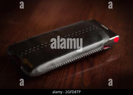 Téléphone noir dans une couverture repose sur une table en bois Banque D'Images
